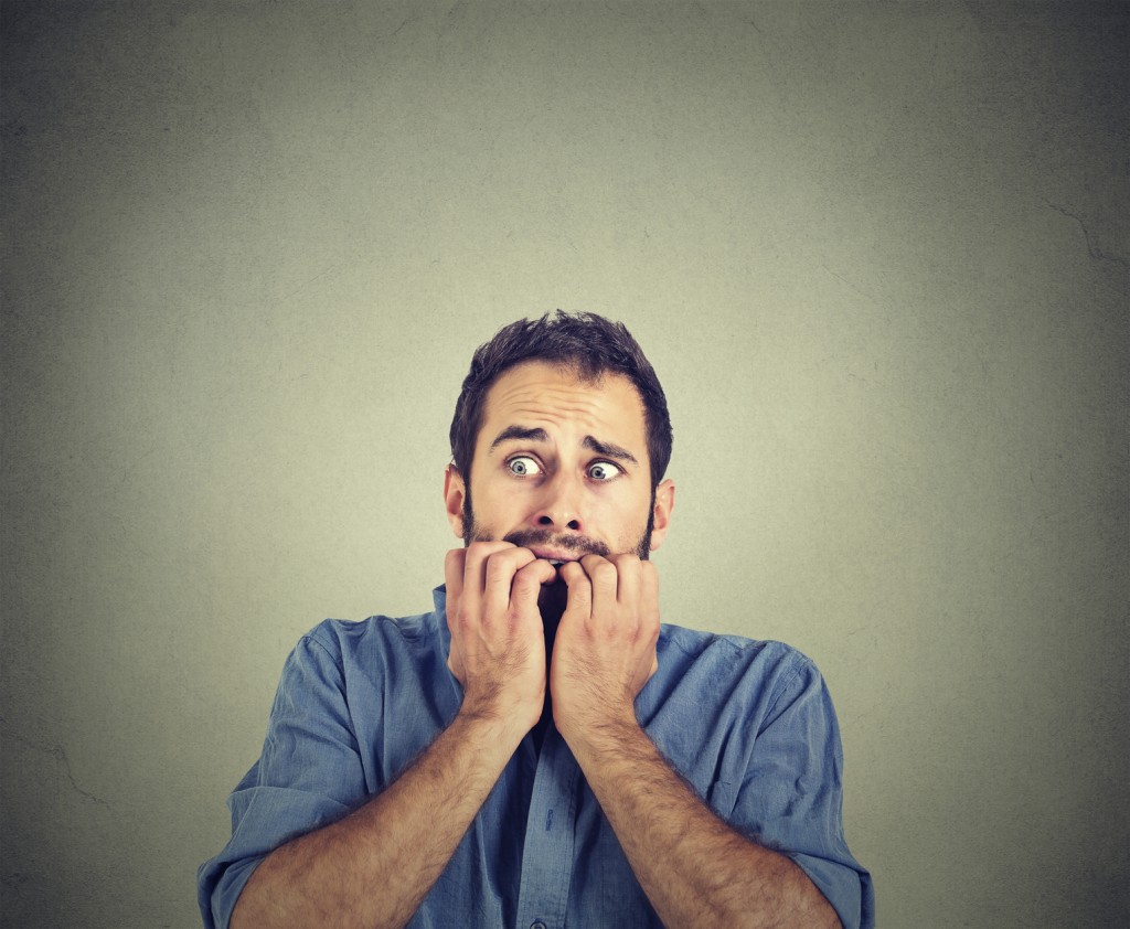 Portrait anxious young man biting his nails fingers freaking out